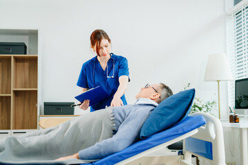 A nurse in blue scrubs conducts a bedside checkup for a senior patient in a bright room,...