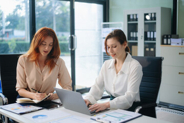 Businesswoman leading team meeting and using tablet and laptop computer with financial