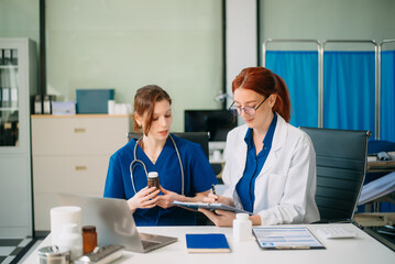 Doctor and nurse team using tablet to review medical results. Diverse healthcare professionals in modern hospital clinic