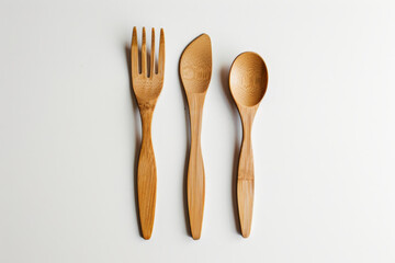 Minimalist top-down view of natural wooden cutlery: a large spoon, a fork, and a smaller spoon, on a clean white background.