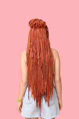Young woman with dreadlocks on pink background, back view