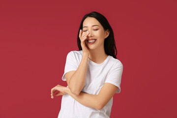 Fototapeta premium Young Asian woman laughing on red background