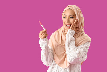 Obraz premium Beautiful Muslim woman with pregnancy test on purple background