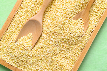 Yellow millet grain in wooden plate with scoop, Food ingredient, Top view