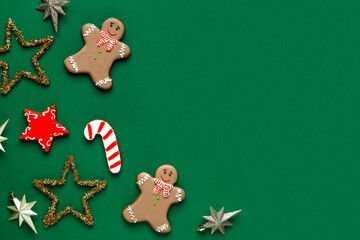 Gingerbread cookies with Christmas decor on green background