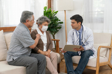 Doctor man explaining health examination results with Asian couple elderly patient at home visit. Retirement health care and life insurance concept