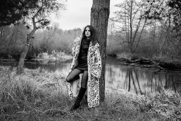 Portrait of a young beautiful dark-haired girl in a leopard fur coat. Black and white photo.