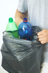 Man holding garbage bag filled with used bottles for recycling. Concept of home waste sorting, plastic pollution awareness and sustainable lifestyle. Environmental responsibility in everyday life.