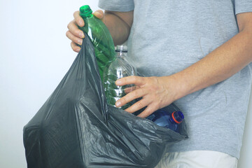 Habits of an environmentally conscious person: a man places empty plastic drink bottles into a...