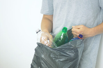 Man holding garbage bag filled with used empty plastic bottles. Recycling habits and global pollution crisis. Responsible behavior of a modern person: collection and separation of household waste.