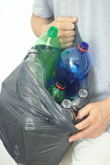 Plastic bottles different colors and sizes in black garbage bag held by man, close-up photo. Concepts of household recycling, waste separation, eco-conscious lifestyle and plastic pollution solution.