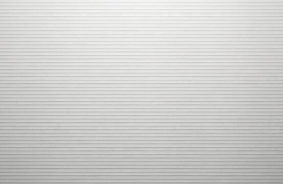 Close-up of textured grey paperboard with horizontal ribbed stripes. Natural craft material features a subtle grain and clean lines, ideal for packaging, backgrounds, or design projects.