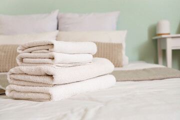 Stack of white clean towels on bed in bedroom, closeup