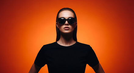 Bold elegance shines through with a stylish woman in sunglasses against a vibrant orange backdrop