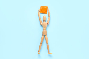 Wooden mannequin with condom on blue background. Sex education