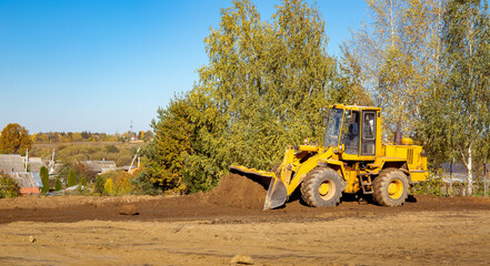 Yellow bulldozer at a construction site. Big wheel excavator leveling and clearing the land plot...