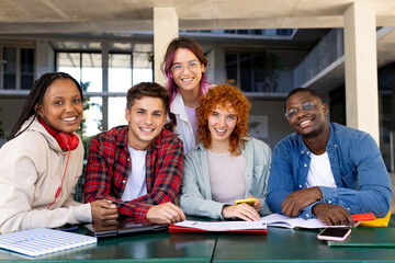 Five students smiling and working together at a table