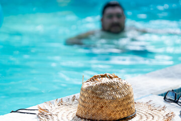 Close up of a straw hat and other objects of a local Costa Rican man taking a dip in the pool in Tortuguero, Costa Rica