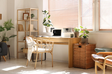 Light office with workplace, modern laptop, houseplants and armchair
