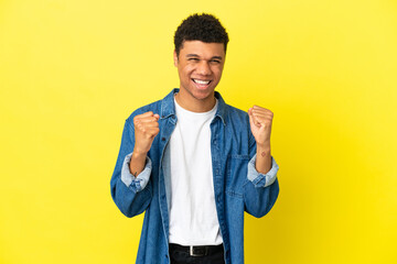 Young African American man isolated on yellow background celebrating a victory in winner position