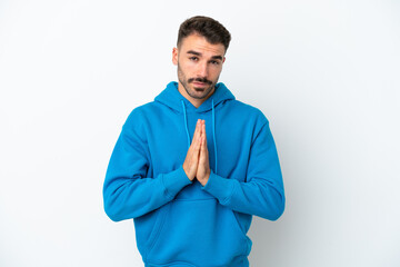 Young caucasian man isolated on white background keeps palm together. Person asks for something