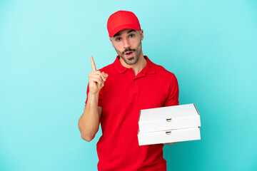 Delivery caucasian man picking up pizza boxes isolated on blue background intending to realizes the...