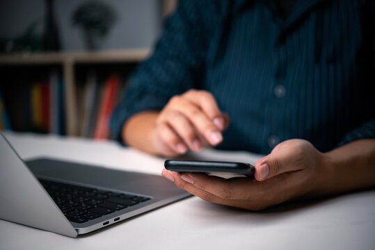 Hands holding phone, interacting with laptop, online learning, mobile banking, digital lifestyle, home office. Technology integration, e-commerce, telecommuting, financial transactions.