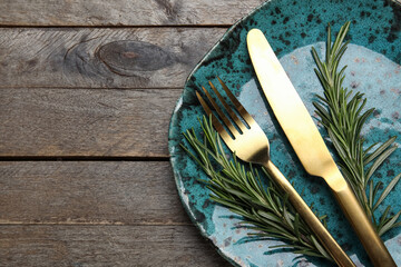 Modern table setting with cutlery and rosemary on wooden background