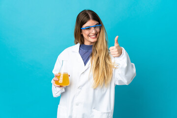Young blonde scientific woman isolated on blue background with thumbs up because something good has...