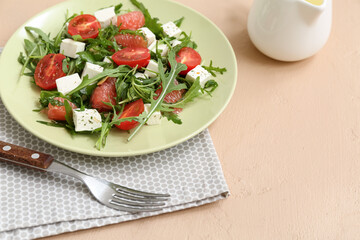 Plate of fresh vegetable salad with napkin and fork on beige background