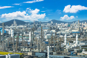 Industrial landscape of a petrochemical plant with the modern city skyline and mountains in the...