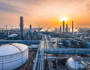 Panorama of a large petrochemical plant and oil refinery complex with wind turbines at golden...