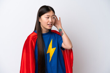 Super Hero Chinese woman isolated on white background listening to something by putting hand on the...