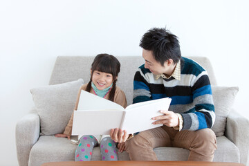 ソファで本を見る親子