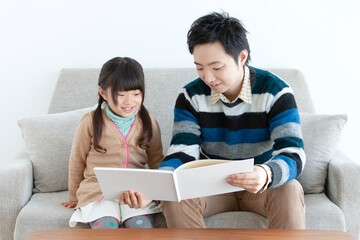 ソファで本を見る親子