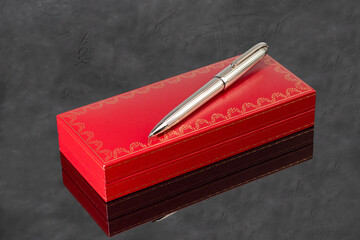 Fountain pen with box on dark gray background. Stationery branded items
