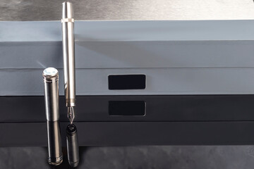 Fountain pen with box on dark gray background. Stationery branded items