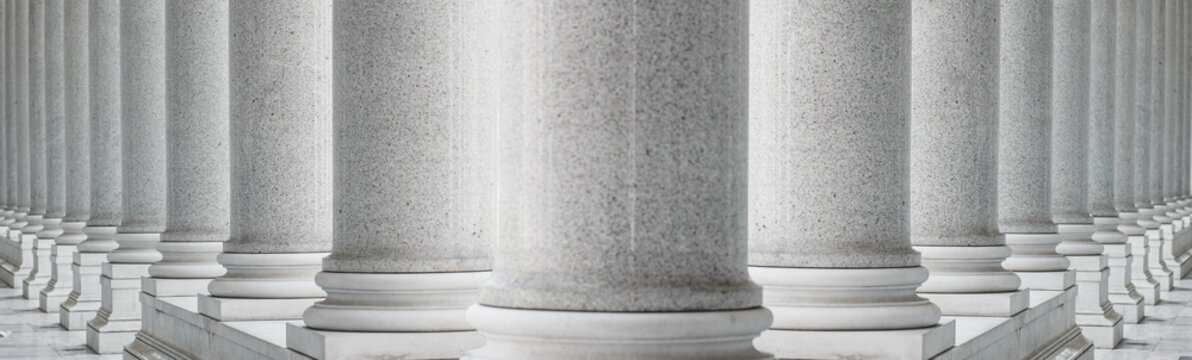 White marble columns in a neoclassical architectural style. Symmetrical row of classical marble columns, structural repetition, and elegant monumental design