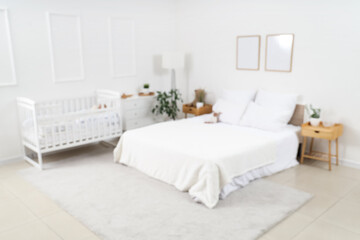 Blurred view of light children's bedroom with crib and plush toy on cozy bed