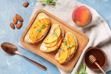 Wooden board of peach bruschetta with ricotta, flax seeds and micro green on blue background