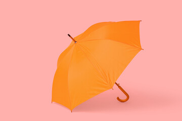 Stylish orange umbrella on pink background