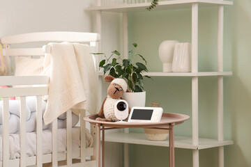 Baby monitor with toy sheep on table in children's bedroom