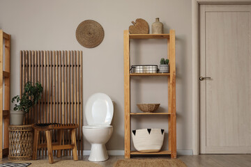 Interior of restroom with toilet bowl, tables and shelf unit