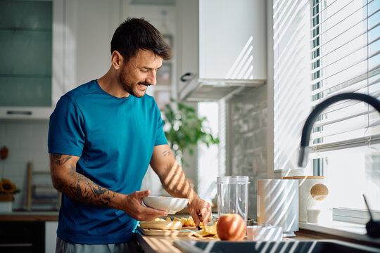 Happy man making himself healthy breakfast in kitchen.