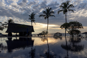 Sunrise over the swimming pool in a hotel with the reflection of the sky