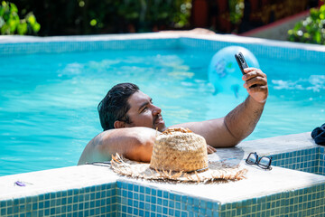 Costa Rican man taking a selfie while relaxing in a pool during his vacation in Tortuguero, Costa Rica