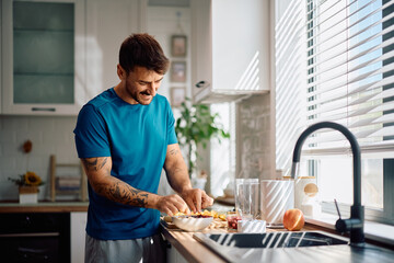 Happy man enjoying in preparing healthy breakfast in kitchen.