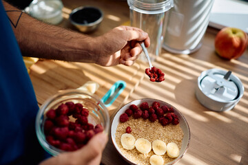 Close up of man making fruit oatmeal for breakfast at home.