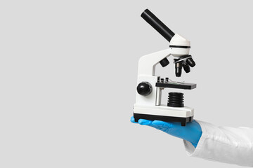 Male scientist with microscope on grey background, closeup