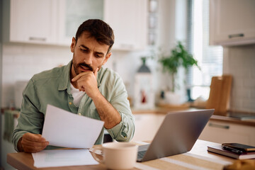Male entrepreneur working on business reports at home.